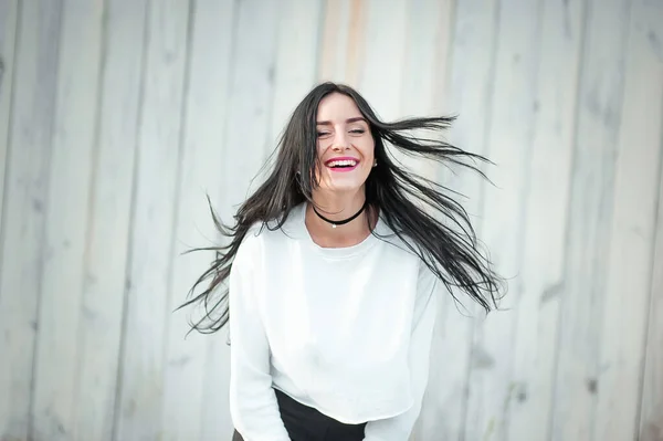Retrato de una hermosa joven en una camiseta blanca con pelo negro. la alegría y la risa degeneran. emociones positivas. Estilo de vida. belleza y juventud. sobre un fondo blanco Emociones positivas y alegres — Foto de Stock