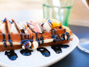 Limonlu Viyana waffle 'ı. Çikolataya bulanmış. Yakın plan. Yukarıdan bak. İçkiler arka planda. Lezzetli kahvaltı.