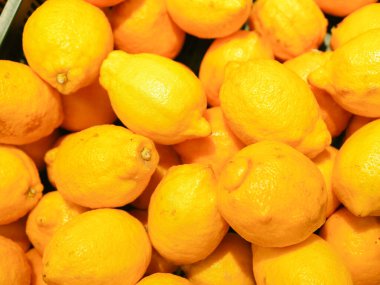 Tezgahta olgun sarı limonlar. Dükkan vitrininde sarı limon koleksiyonu. Yakın plan. Yeni yıl meyve konsepti, taze sıkılmış vitamin suyu.