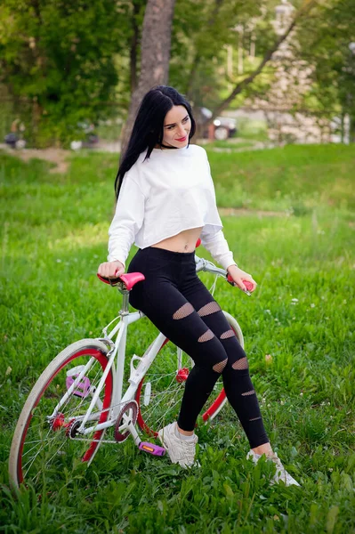Piękna dziewczyna pozująca na rowerze. Biały i czerwony rower. chodzić w naturze. zdrowy tryb życia. Weekend w przyrodzie Portret szczęśliwej pięknej dziewczyny w białej koszulce. miejsce do pisania — Zdjęcie stockowe