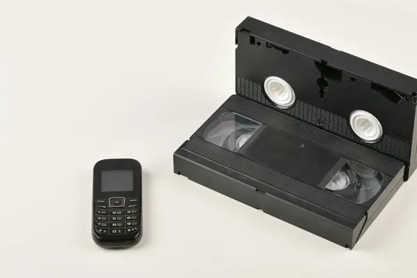 Retroobjekt på en vit bakgrund. Knapptelefon och videokassett. Analog medieteknik från förr. Kopiera utrymme — Stockfoto