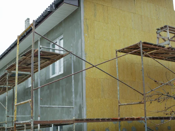 Özel bir evin harici ısınması. Açık hava işi. İşçiler için raylar var. Apartman ısınıyor. Binanın dış onarım çalışmaları, yalıtım ve dış cephenin kaplaması.