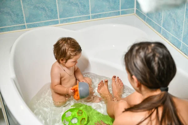 Joint bathing baby and mom. Moms hands wash the girls in the bathroom. A symbol of cleanliness and hygiene education. — Stock Photo, Image