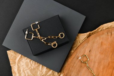 Altın küpeler. Asimetri. Yakın plan. Tahta bir tezgahta yatıyordu. Yukarıdan bak. Mücevher ve mücevher kavramı. Kadınlar için hediyeler. Alışveriş. El işi.