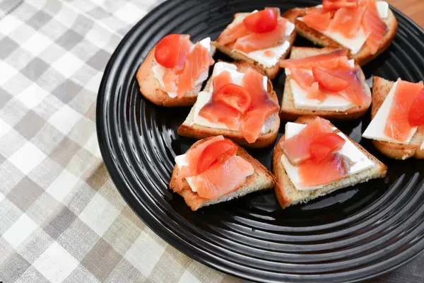 Sandwiches mit rotem Fisch auf einem schwarzen Teller. Blick von oben — Stockfoto