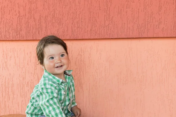 Bambino felice su uno sfondo di corallo. Testa e spalle ritratto di carina bambina dagli occhi azzurri guardando la fotocamera e ridendo su un colore corallo — Foto Stock