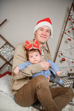 Noel geçmişinde çocuklu bir baba. Küçük bir çocuğun kafasında kırmızı boynuzlar. Yeni yıl. Noel kutlaması. Güzel bir aile Noel ağacının yanında oturur. Süveter giyen yakışıklı adam. Küçük çocuk.