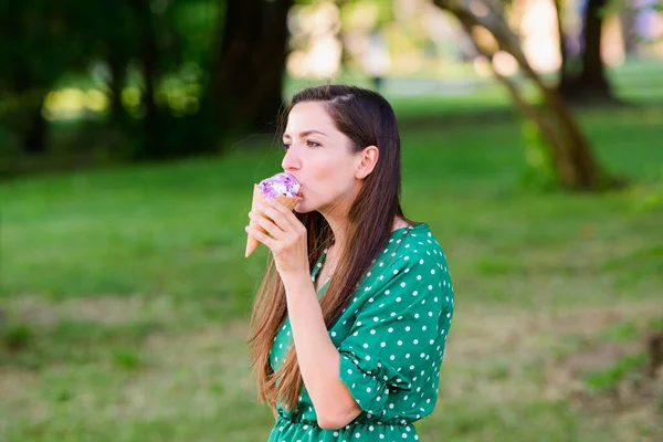 girl eating ice cream on a green background. place for an inscription. Portrait of a young urban woman with ice cream on a green background. girl eating ice cream in a green dress with white polka dot