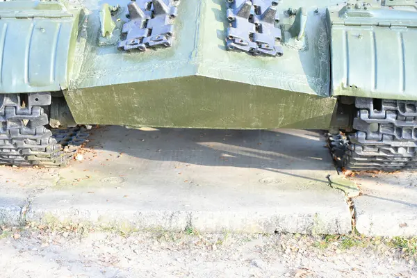 Tank wheels close-up. Iron tracks of a heavy military tank. Iron caterpillars and wheels of a military heavy tank. View of the front part of the green caterpillar of the tank standing on the ground wi — Stock Photo, Image