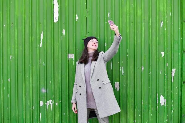 Meisje op een groene achtergrond. In een warme grijze jas. Portret van het mooie meisje op een groene achtergrond — Stockfoto