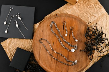 Zincirli gümüş küpeler. Yakın plan. Tahta bir tezgahta yatıyordu. Yukarıdan bak. Mücevher ve mücevher kavramı. Kadınlar için hediyeler. Alışveriş. El işi.