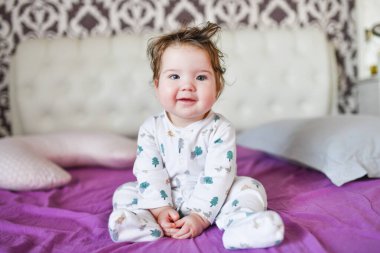 Yatakta oturan küçük bir çocuğun portresi. Yatakta oturan küçük bir bebeğin portresi. Yatakta oturan küçük bir çocuğun portresi, dik duruyor, tek kaşını kaldırmış. 