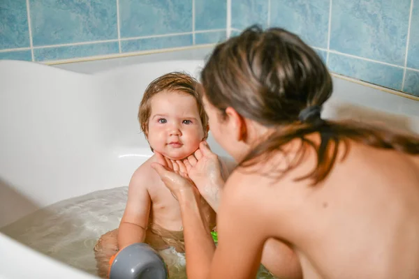 Joint bathing baby and mom. Moms hands wash the girls in the bathroom. A symbol of cleanliness and hygiene education. — Stock Photo, Image