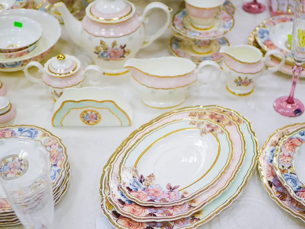 Celebratory china. decorated with flowers. Soft colors. Luxurious dining table for gourmet dinners at festive or formal occasions. Unusual porcelain tableware with gold decor.