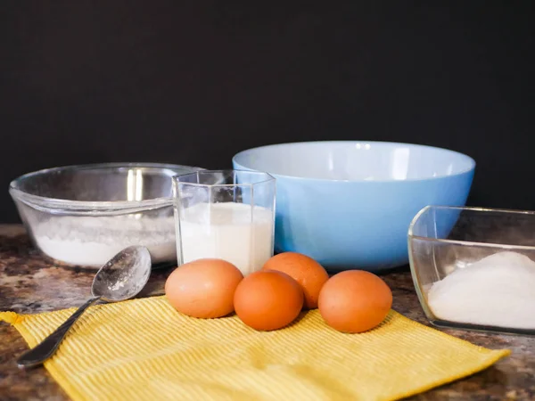 Υλικά για το ψήσιμο ζύμης. αλεύρι, αυγά, γάλα. Υλικά ψησίματος. Κουτάλι σε μαρμάρινο τραπέζι. Προετοιμασία για μαγείρεμα. — Φωτογραφία Αρχείου