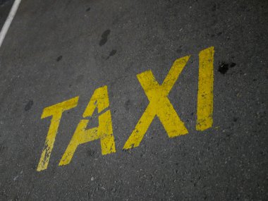 Asfaltta sarı taksi yazıları var. Park yeri ve taksi şoförü için bir yer..