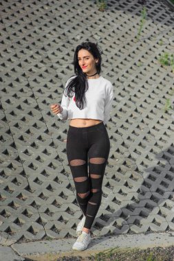 Güzel bir atletik kızın portresi. güzellik ve sağlık konsepti. Beyaz maik giymiş esmer ve siyah paçavralı tembel.