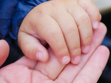 Sevgi dolu bir anne bir çocuğun elini tutar. Yeni doğmuş bir bebeğin eli