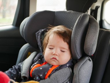 Çocuk çocuk araba koltuğunda uyuyor. Arabada çocuk güvenliği var. Seyahat ederken uyuyan bebek.