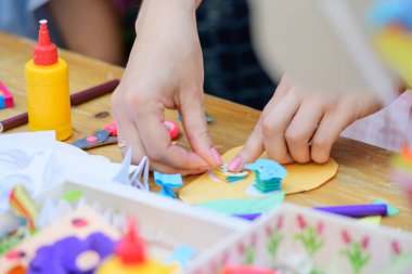 Çocuklar için eğitim çemberi. Bir grup çocuk sınıflarında sandalyede oturuyorlar. Erkek öğretmen, kadın. Renkli malzemelerden figürlerin nasıl yontulduğunu gösterir.