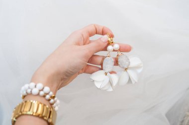 Evlilik küpeleri. Gelinin ellerinde beyaz var. Düğün için küpe seçimi. Evlenmeye hazır. Düğün alışverişi. Düğün sabahı ve mücevher aksesuarları ve dekorasyon konsepti..