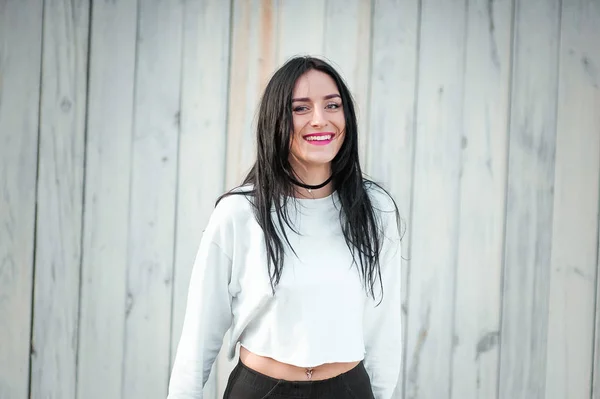 Joven chica positiva. sobre un fondo de madera claro. Con el pelo negro y una hermosa figura. Primer plano retrato de chica caucásica bastante joven con la cara feliz y hermosa sonrisa. Aislado sobre respaldo blanco — Foto de Stock