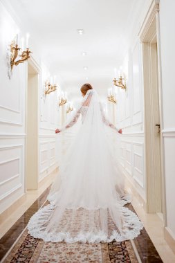 Beyaz elbiseli bir kız beyaz bir koridorda yürüyor. Koridorda elbisesiyle yürüyen güzel bir moda kızı. Antik çağlardan kalma kıyafetler. Tarihi çağ. Yukarıdan görünüm.