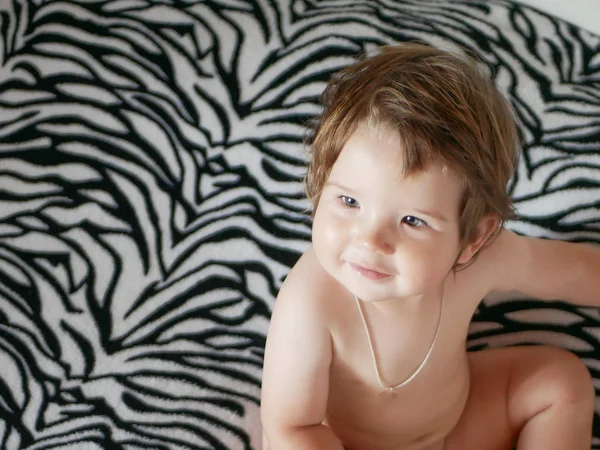 Naakt uitzicht op de babytop. Tegen de achtergrond van een zebra. Zebra deken. Leuke blonde baby met een naakte romp — Stockfoto