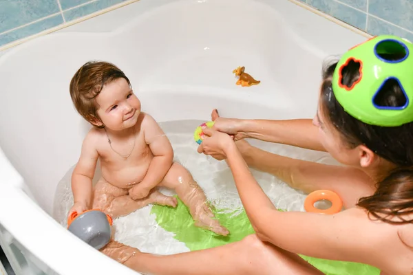 Joint bathing baby and mom. Moms hands wash the girls in the bathroom. A symbol of cleanliness and hygiene education. — Stock Photo, Image