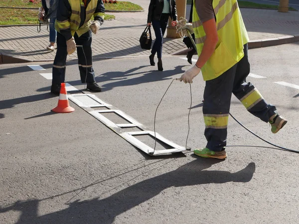 Road marking. Drawing a road marking. spraying in road construction. Worker draws a white line on the surface of the street.