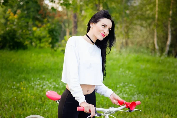 Schöne Mädchen posiert auf einem Fahrrad. weiß-rotes Fahrrad. Spaziergang in der Natur. Gesunder Lebensstil. Wochenende in der Natur Porträt eines glücklichen schönen Mädchens in einem weißen T-Shirt. Platz zum Schreiben — Stockfoto