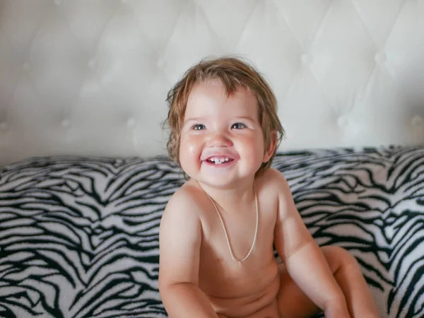 De naakte baby lacht. Lach maar tussen je tanden. Gelukkig lachende baby. Witte tanden van een pasgeboren baby. Natuurlijke lach. Zorgeloze baby. — Stockfoto