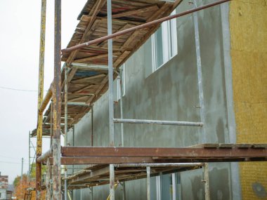 Özel bir evin harici ısınması. Açık hava işi. İşçiler için raylar var. Apartman ısınıyor. Binanın dış onarım çalışmaları, yalıtım ve dış cephenin kaplaması.