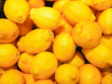 Tezgahta olgun sarı limonlar. Dükkan vitrininde sarı limon koleksiyonu. Yakın plan. Yeni yıl meyve konsepti, taze sıkılmış vitamin suyu.