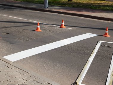 Yol işaretleri. Yol işareti çiziyorum. Yol inşaatında sprey sıkmak. İşçi sokağın yüzeyine beyaz bir çizgi çekiyor..