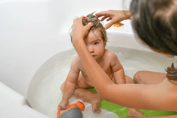 Mom washes the babys head. Joint bathing baby and mom. A symbol of cleanliness and hygiene education. — Stock Photo, Image