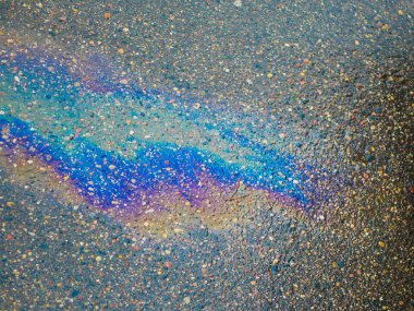 Kaldırımda bir benzin birikintisi. Yakın plan. Islak asfalt yolda sızan benzin. Islak asfalt yolda sızan renkli benzin. 