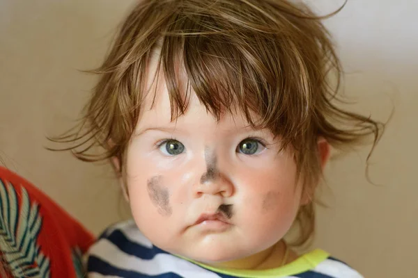 Ele manchou o rosto de uma criança. nos braços da mãe. A criança é pintada com aquarelas. A criança depois de aplicar todo o rosto manchado e sujo da criança — Fotografia de Stock