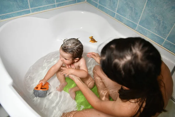 Mom washes the babys head. Joint bathing baby and mom. A symbol of cleanliness and hygiene education. — Stock Photo, Image