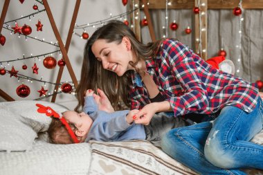 Noel geçmişinde çocuklu bir anne. Küçük bir çocuğun kafasında kırmızı boynuzlar. Yeni yıl. Noel kutlaması