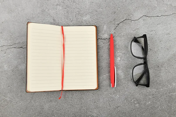 Cuaderno negro y pluma roja. Cuaderno en blanco y bolígrafo rojo. Cuaderno en blanco y pluma roja sobre fondo de hormigón gris. vista desde arriba . —  Fotos de Stock