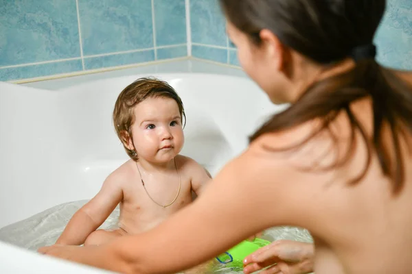 Joint bathing baby and mom. Moms hands wash the girls in the bathroom. A symbol of cleanliness and hygiene education. — Stock Photo, Image