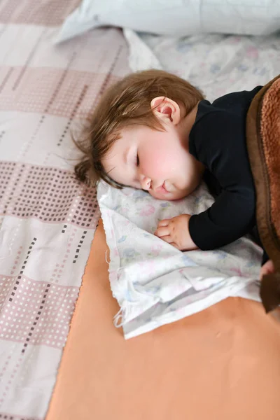 El sueño diurno del bebé. Sueño saludable durante el día para el recién nacido. El niño duerme en un capullo ortopédico infantil sobre la cama. descanso infantil después de un juego activo con los padres — Foto de Stock