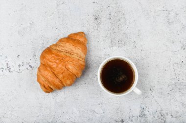 Kruvasan ve fincan. özel bir arka planda. Taze Fransız kruvasanı. Tahta bir arka planda. Yukarıdan bak. Bir ayçöreğiyle sabah kahvaltısı. Evde bir Fransız kahvaltısı hazırlanır. Sobanın üstünde.