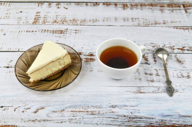 Açık ahşap arka planda kahveli cheesecake. Kahve dükkanında kahve, fotokopi odası. Açık beton arka planda New York peynirli keki, üst manzara. Klasik cheesecake ve bir fincan kahve..