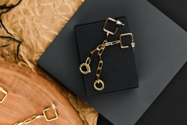 Altın küpeler. Asimetri. Yakın plan. Tahta bir tezgahta yatıyordu. Yukarıdan bak. Mücevher ve mücevher kavramı. Kadınlar için hediyeler. Alışveriş. El işi.