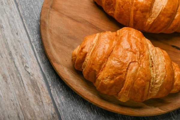 Croissant close-up. Verse Franse croissant. Naar op van hout back-up. Zicht van bovenaf. Ochtend ontbijt met een croissant. Frans ontbijt — Stockfoto