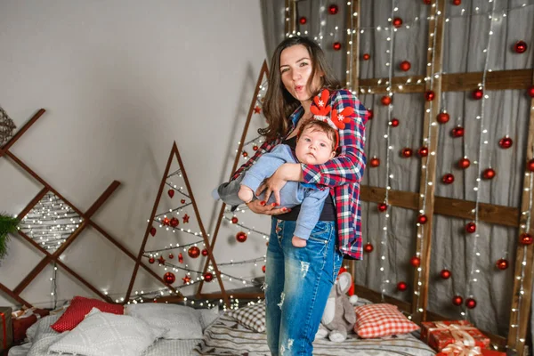 Noel 'de anneyle bebek. Mutlu aile annesi ve küçük oğlu Noel tatillerinde evde oynuyorlar. Yeni yıl tatili. Annenle birlikte Noel ağacıyla süslenmiş bir odada bebek. Po — Stok fotoğraf