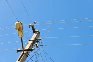 Bulutlu mavi bir gökyüzünün arka planında lamba direğiyle elektrik iletimi için kullanılan eski beton bir elektrik direği. Beni geçersiz kıl. Elektrik tedarikçisi Thod 