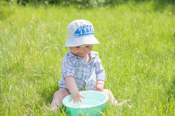 Un heureux garçon heureux qui frapperait dans le bassin. à l'extérieur en été, pulvérisation d'eau. .child joue avec un bassin d'eau sur l'herbe. Bébé garçon drôle jouant dans la rue avec de l'eau et des bulles. Mignon — Photo